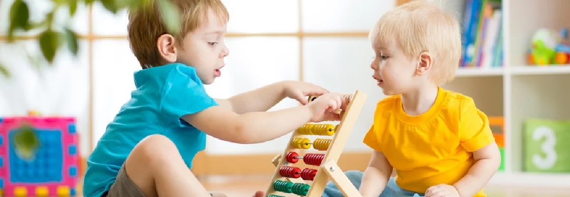 Zwei Kinder spielen mit einem Rechenschieber.